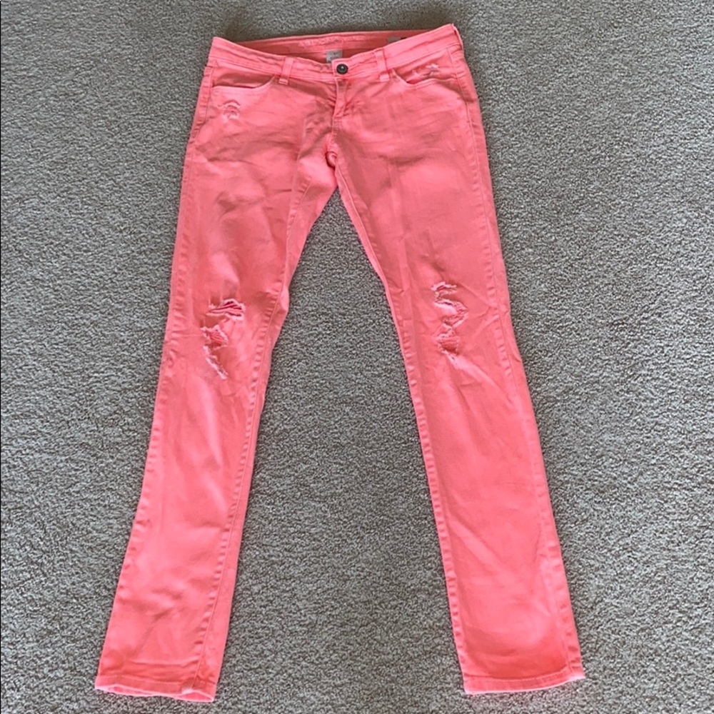 Juniors bright salmon colored distressed jeans